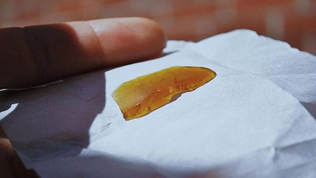 Close-up of a hand holding an infused pre-roll, representing the finished product ready for consumption.