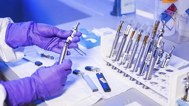 An array of vape pen components laid out, including cartridges and batteries.