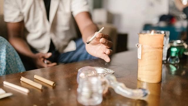 Close-up of hands expertly shaping a joint, focusing on even distribution of cannabis for a smooth burn.