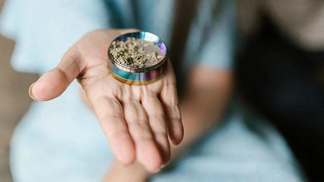 Close-up of hands holding a grinder, focusing on a consistency that's not too fine but not too chunky.