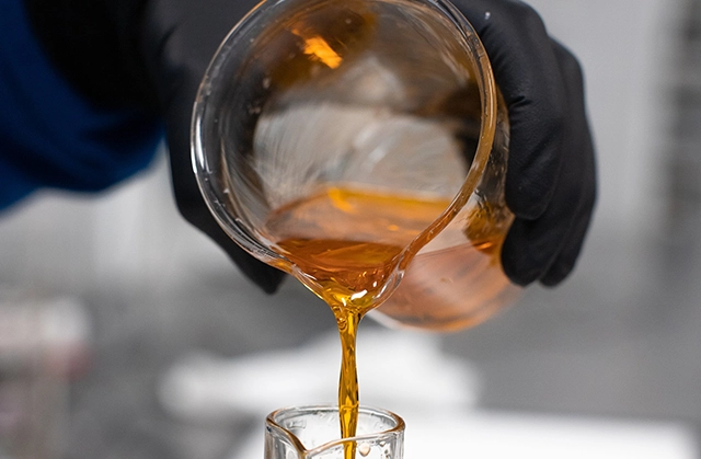 Golden cannabis-infused oil pouring from a jar, commonly used in cannabis topicals