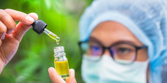 A person extracting a THC tincture with a pipette, showcasing the precise dosing capability of tincture droppers.
