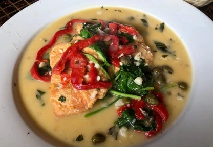 Creamy soup with spinach and red peppers in a white bowl